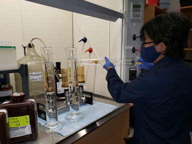 Water Quality Scientist tests water quality samples under a fume hood.
