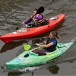 Two kayakers paddle down the river.