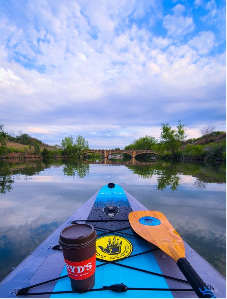 Coffee mug and kayaking or paddling equipment looking out towards river.