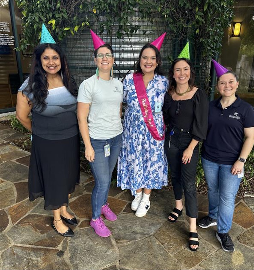 Five women together wearing party hats