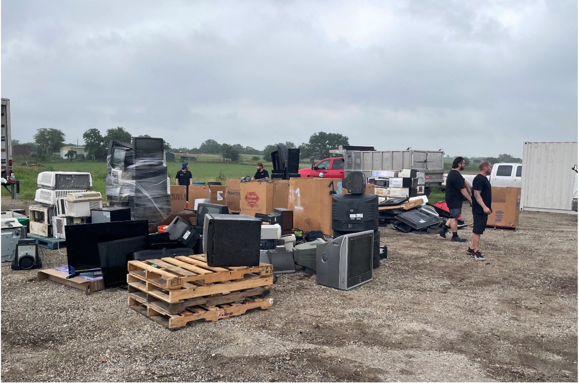 Piles of trash such as old TVs, boxes, and electronic items are stacked in an open area.