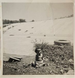 A small child sits in a concrete area