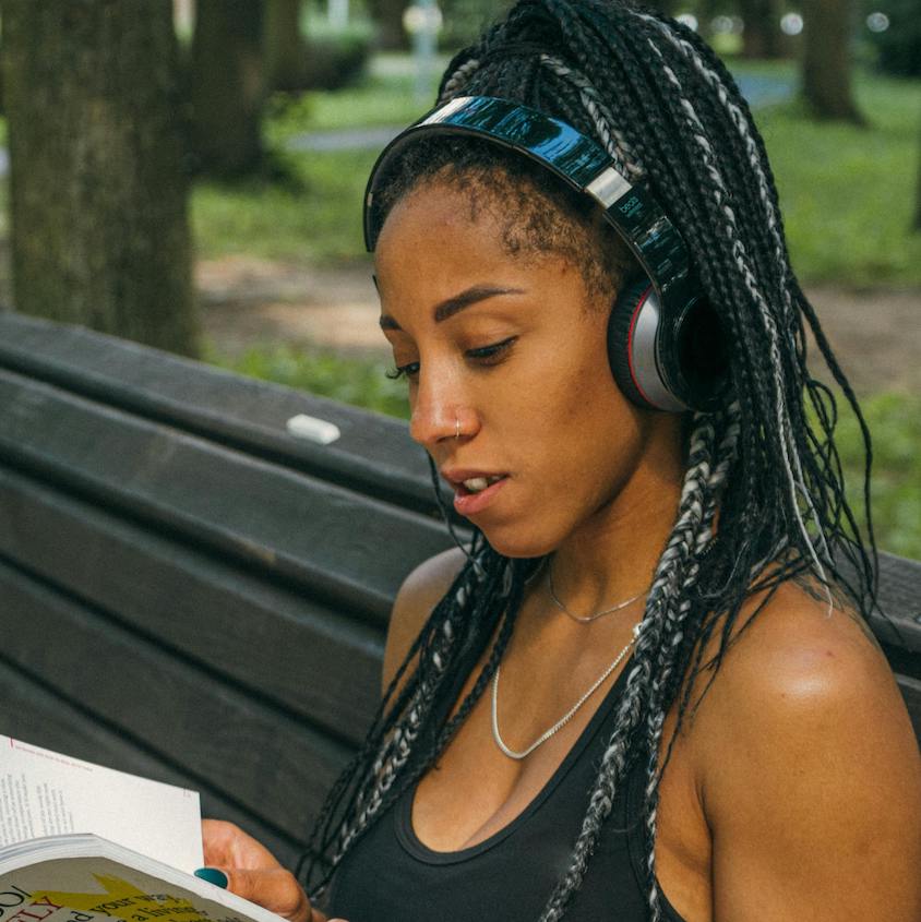 Woman reading a book with headphones on