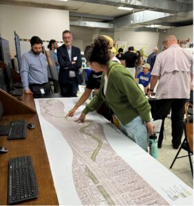 People gather around a large map during the Westside Creeks Ecosystem Restoration Project