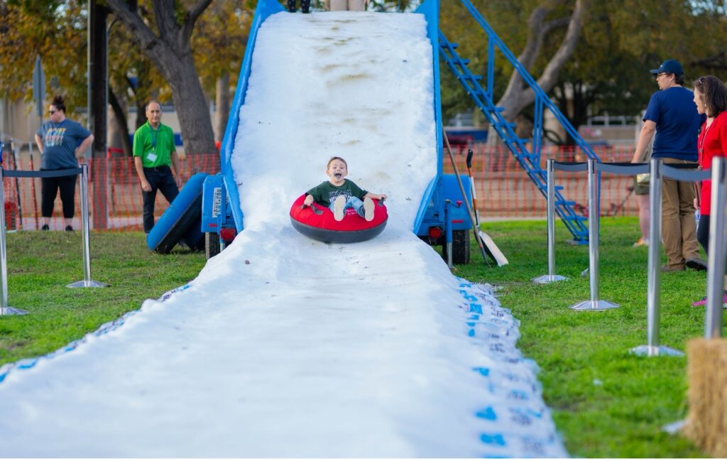 A child slides down the snow slide at the River of Lights Event