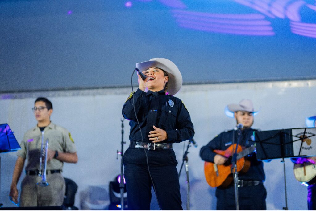 A woman police officer sings into a microphone on stage