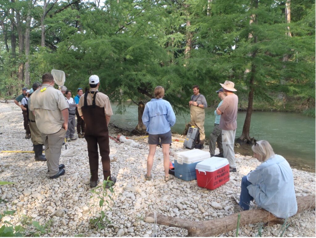 A group of people stand together near the San Antonio River Bank