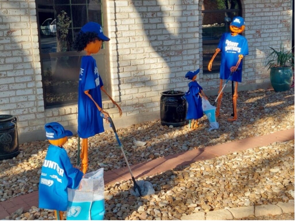 Four models made of pumpkins pick up trash in a yard as a halloween display