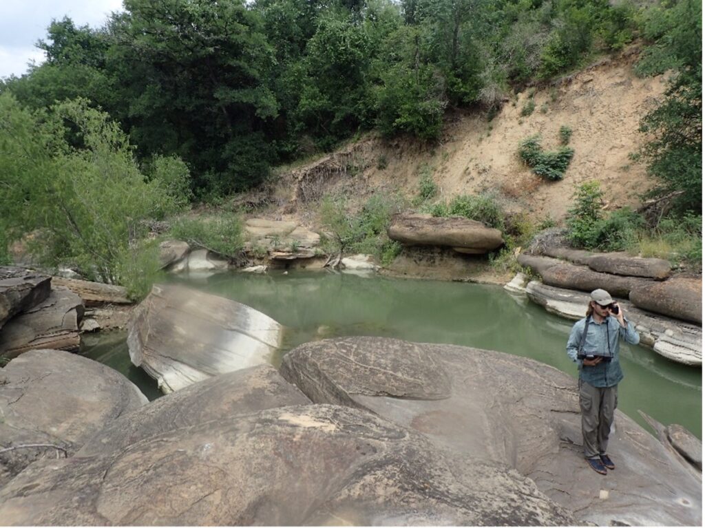 Austin Davis walks around river bank during survey