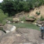 Austin Davis walks around river bank during survey