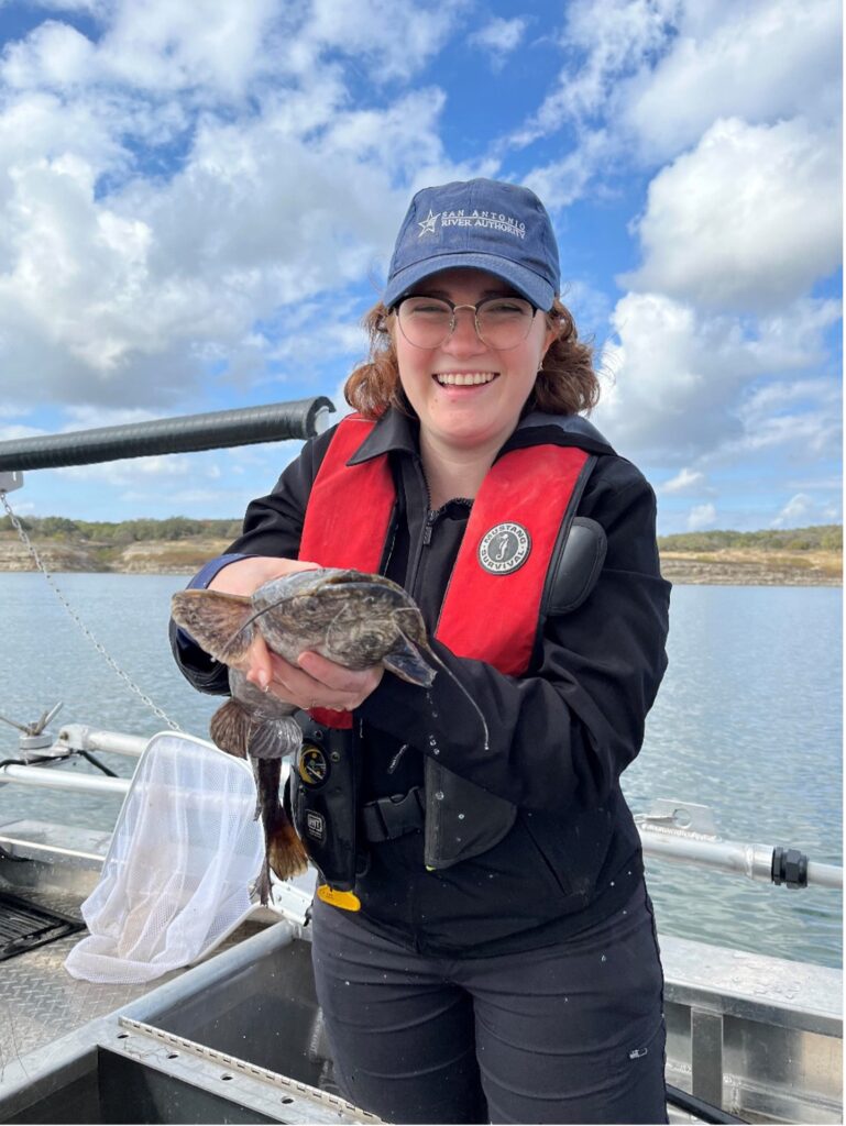 Scientist holds catfish while on a boat