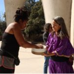 Two women gather around a bowl